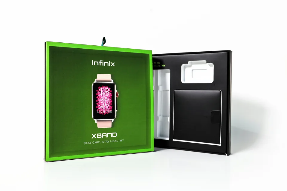 Infinix 智能手表包装盒实拍；绿色盒盖与黑色内部结构同时展示，盒内可见产品及配件分区。