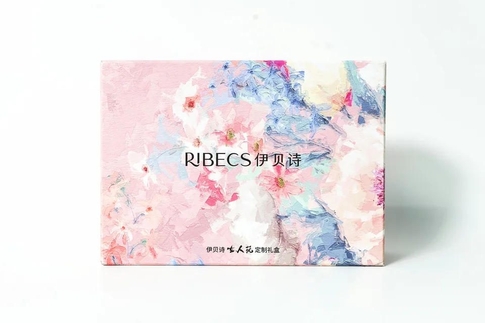 伊贝诗美妆定制礼盒实拍；礼盒正面以花卉图案和品牌文字展开，展示柔和配色的包装外观。